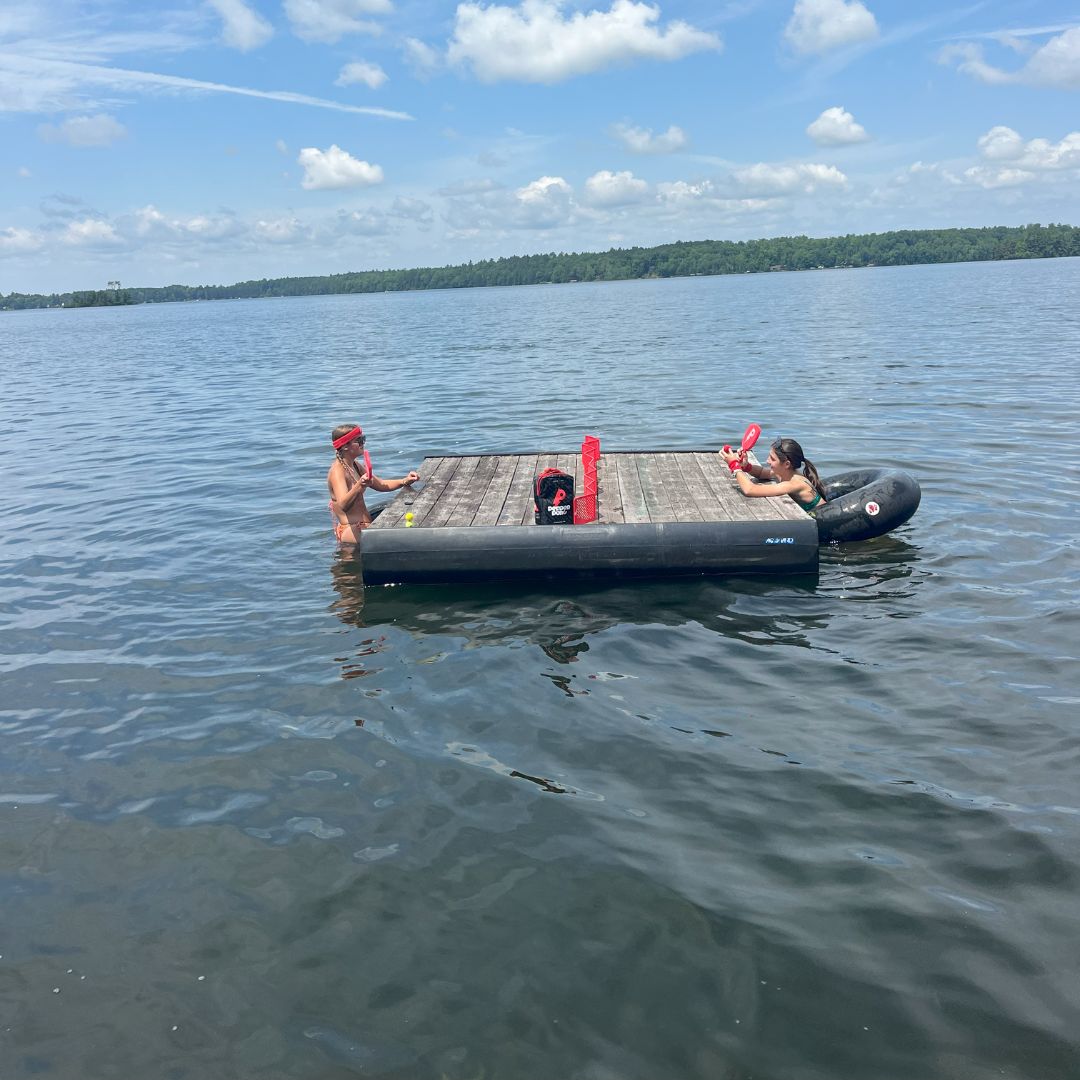 two friends swimming and playin pepper pong on floating doc