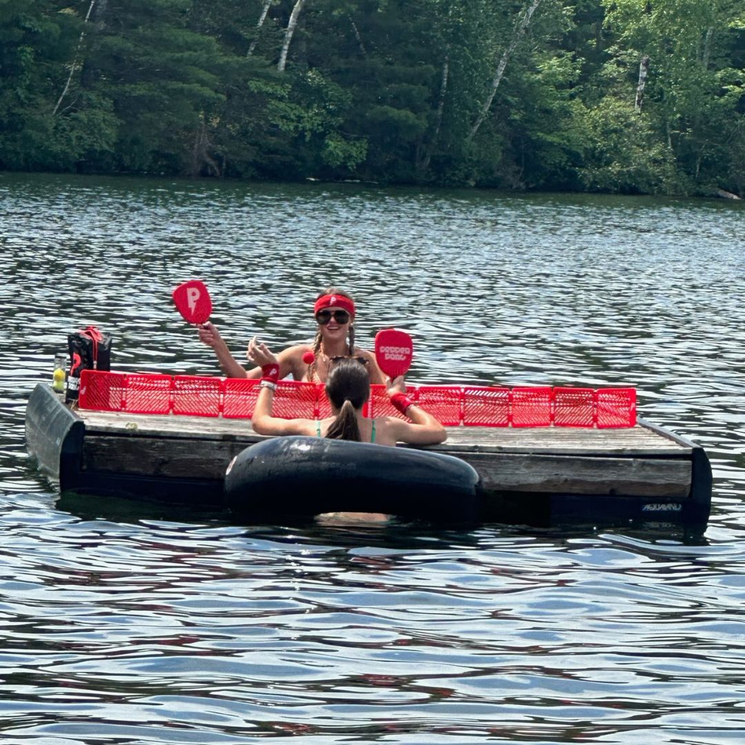 girls swimming in lake playing pepper pong on wooden floating dock